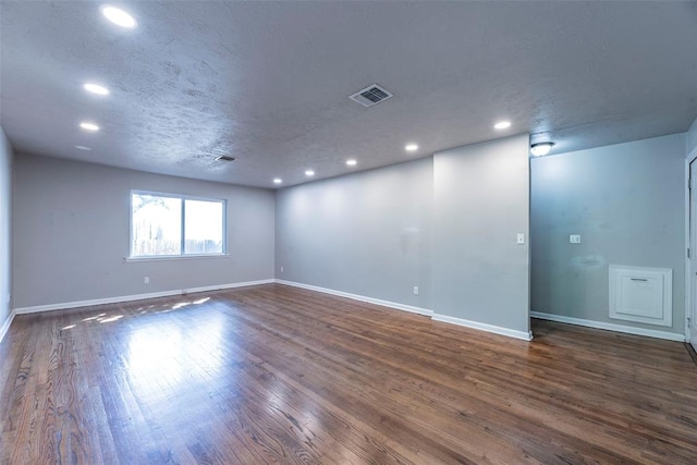 spare room featuring a textured ceiling and dark wood-type flooring