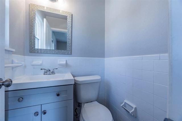 bathroom featuring vanity, tile walls, and toilet