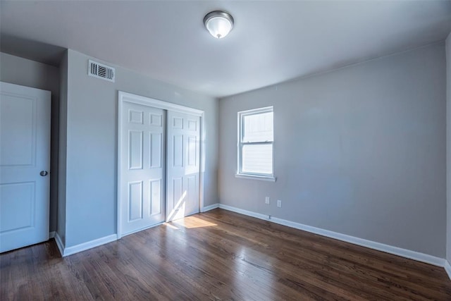 unfurnished bedroom with dark hardwood / wood-style flooring and a closet