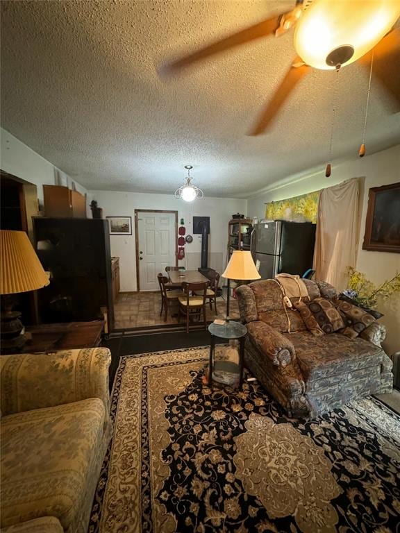 living room with ceiling fan and a textured ceiling