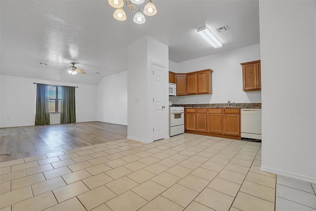 kitchen featuring light wood-type flooring, a textured ceiling, white appliances, ceiling fan with notable chandelier, and sink