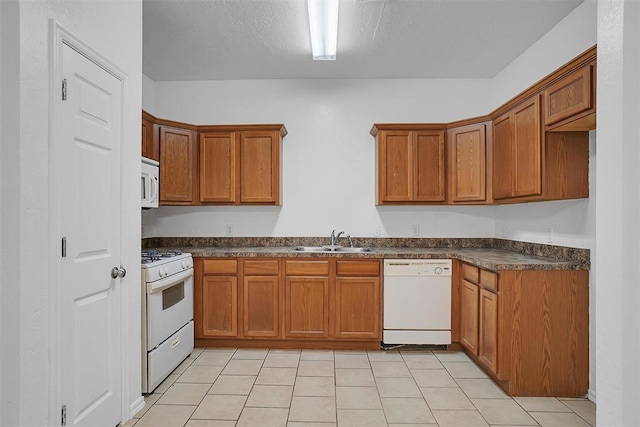 kitchen featuring white appliances, sink, and light tile patterned floors