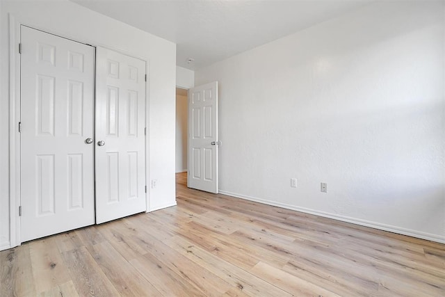 unfurnished bedroom with light hardwood / wood-style floors and a closet