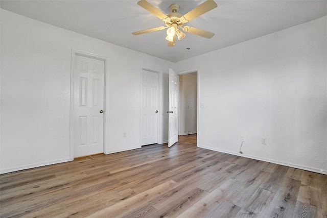 unfurnished bedroom featuring ceiling fan, multiple closets, and light hardwood / wood-style flooring