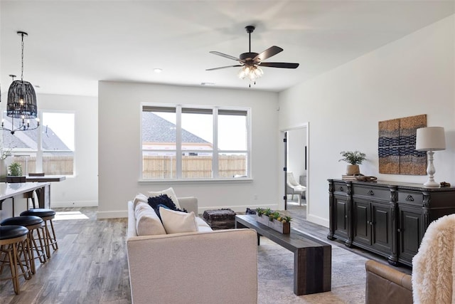 living room featuring wood-type flooring and ceiling fan with notable chandelier