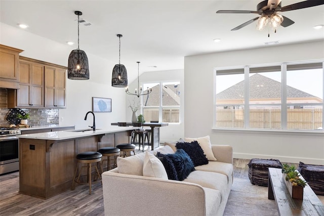 living room with dark hardwood / wood-style floors, sink, and ceiling fan with notable chandelier