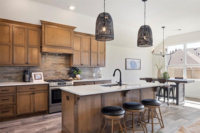 kitchen featuring stainless steel gas stove, an island with sink, dark hardwood / wood-style floors, and sink