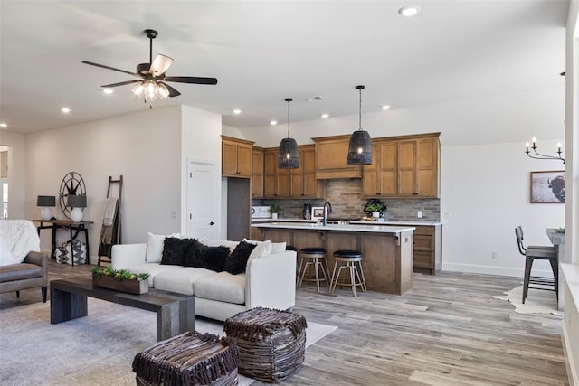 living room featuring sink, light hardwood / wood-style floors, and ceiling fan with notable chandelier