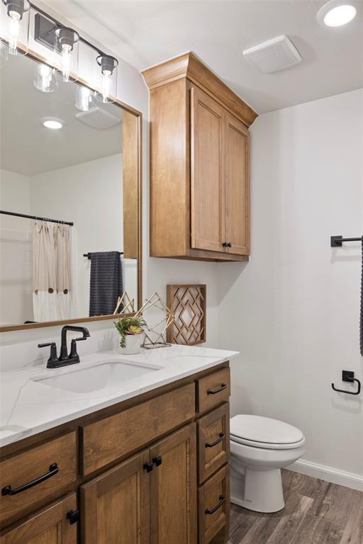 bathroom with wood-type flooring, vanity, toilet, and a shower with curtain