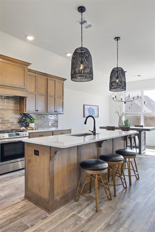 kitchen featuring hardwood / wood-style floors, a large island with sink, sink, and stainless steel range