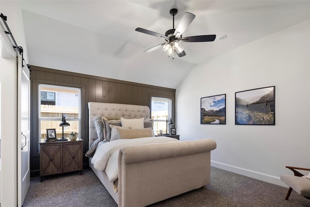 bedroom with wood walls, lofted ceiling, dark colored carpet, ceiling fan, and a barn door