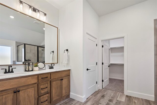 bathroom with hardwood / wood-style floors, vanity, and a shower with door