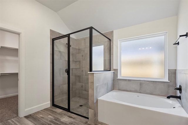 bathroom featuring hardwood / wood-style flooring, vaulted ceiling, and independent shower and bath