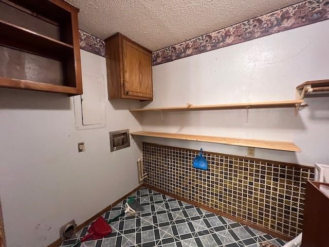 clothes washing area featuring electric dryer hookup, cabinets, a textured ceiling, and hookup for a washing machine