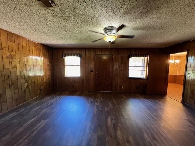 spare room with a wealth of natural light, wood walls, and dark hardwood / wood-style floors