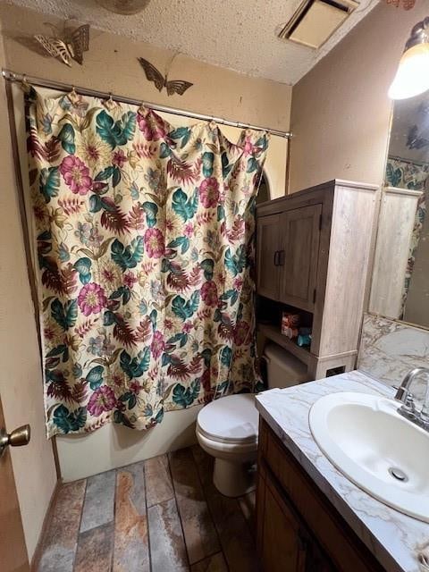 full bathroom with shower / tub combo with curtain, vanity, a textured ceiling, and toilet