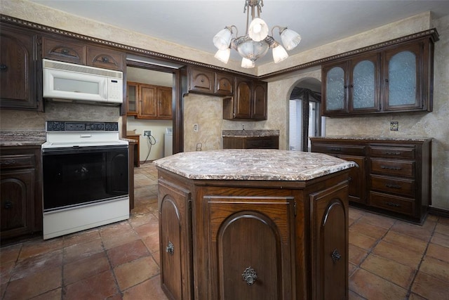 kitchen featuring electric stove, a center island, dark brown cabinetry, decorative light fixtures, and a chandelier