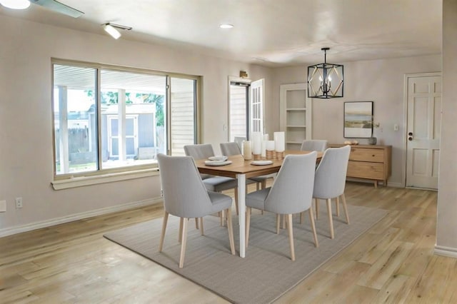 dining space with light hardwood / wood-style flooring and a notable chandelier