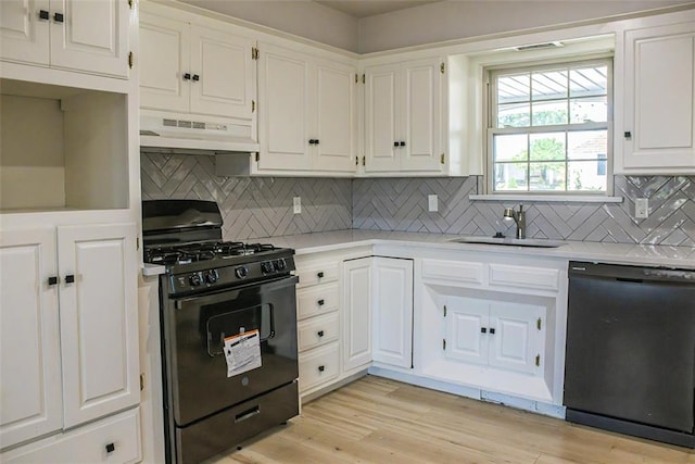 kitchen with light wood-type flooring, tasteful backsplash, sink, black appliances, and white cabinetry