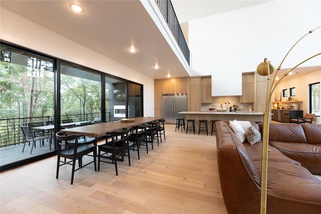 dining space featuring a towering ceiling and light hardwood / wood-style floors