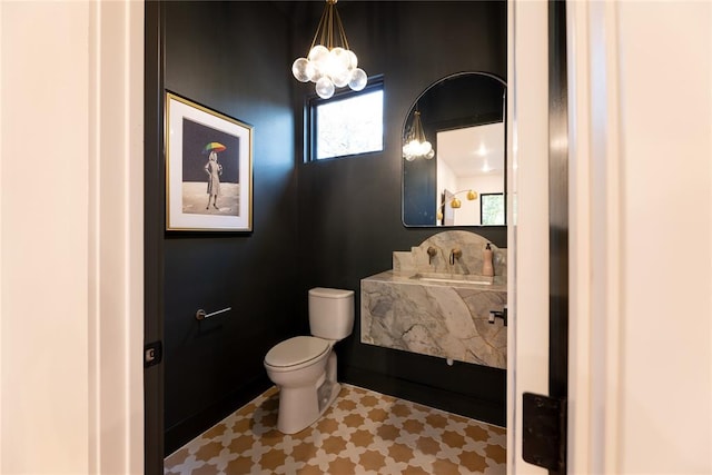 bathroom featuring an inviting chandelier and toilet