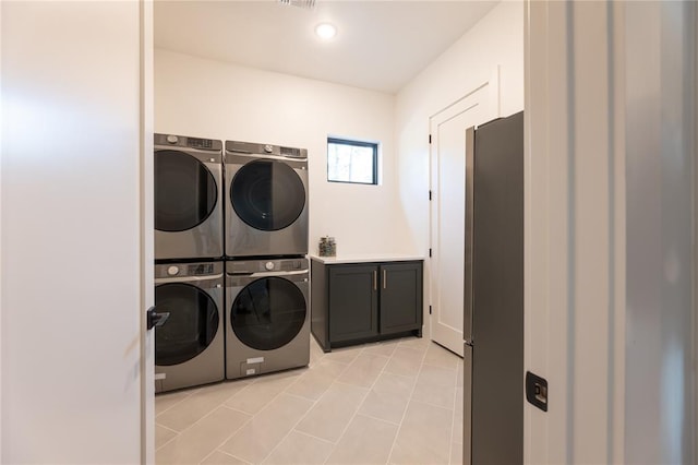 washroom featuring cabinets, stacked washer / dryer, and washing machine and dryer