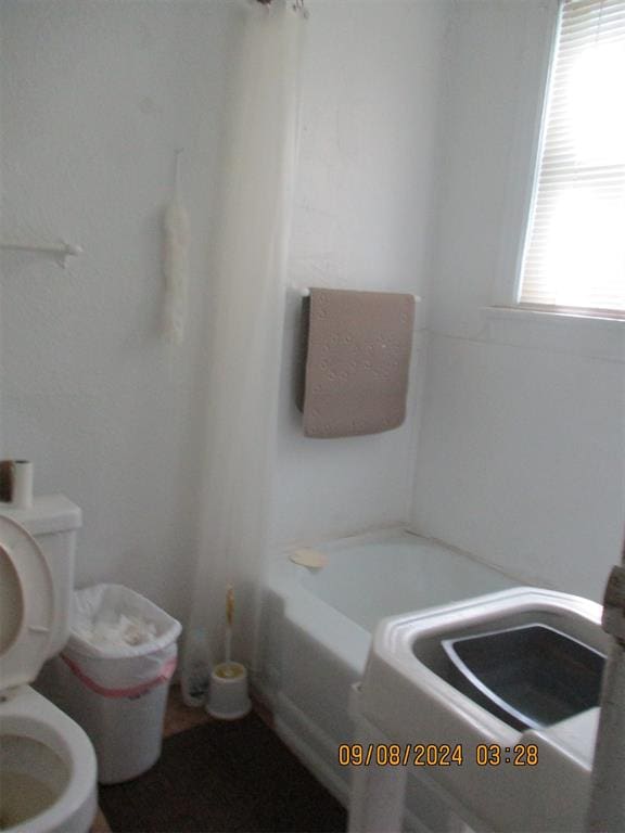 bathroom featuring toilet and a tub to relax in