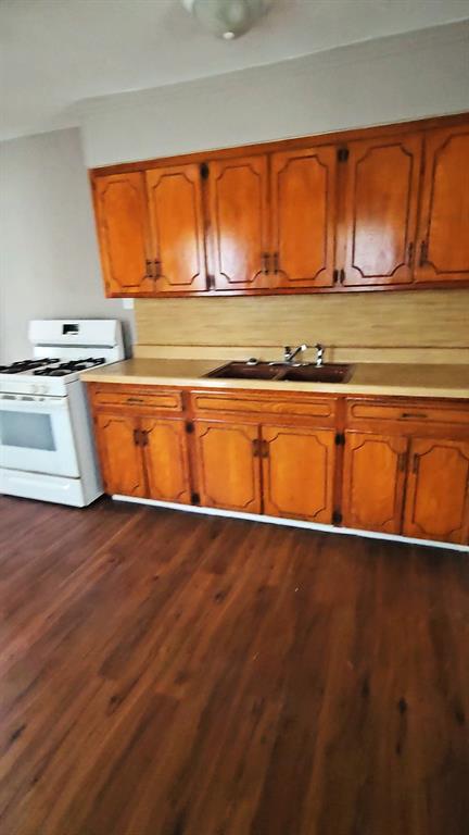 kitchen with dark hardwood / wood-style flooring, white gas range, and sink