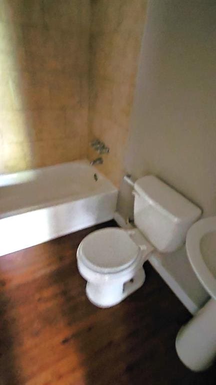 bathroom featuring wood-type flooring, bathing tub / shower combination, and toilet