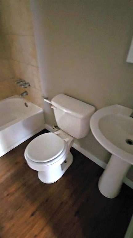 bathroom featuring hardwood / wood-style flooring, toilet, and tiled shower / bath