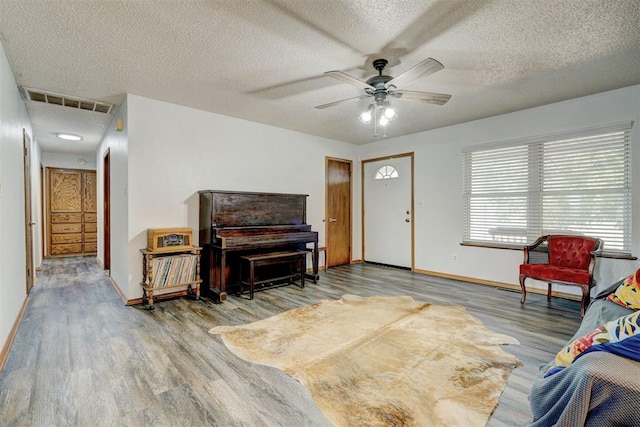 living room featuring hardwood / wood-style floors, ceiling fan, and a textured ceiling