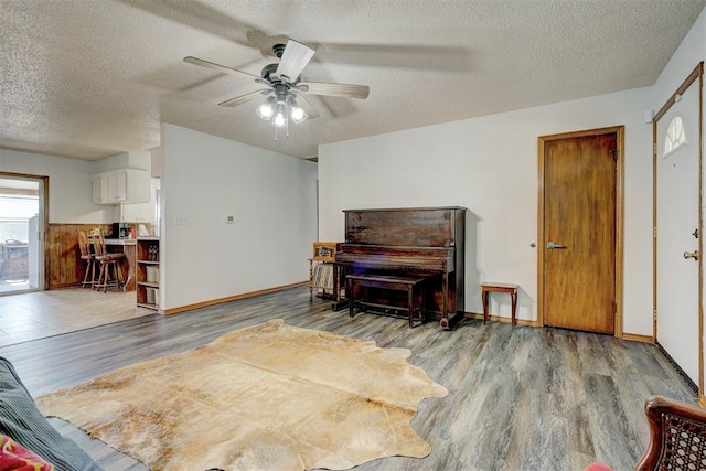 living room with hardwood / wood-style floors, ceiling fan, and a textured ceiling