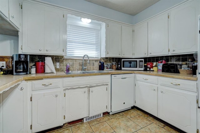 kitchen featuring white cabinetry, sink, tasteful backsplash, a textured ceiling, and white appliances