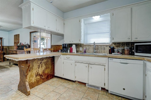 kitchen with white cabinets, a textured ceiling, white dishwasher, and sink