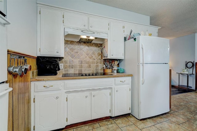 kitchen featuring backsplash, a textured ceiling, black electric cooktop, white refrigerator, and white cabinets