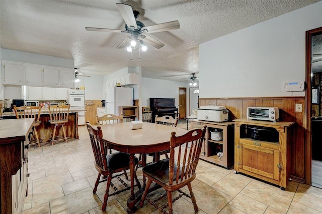 dining space featuring wooden walls, light tile patterned flooring, and a textured ceiling