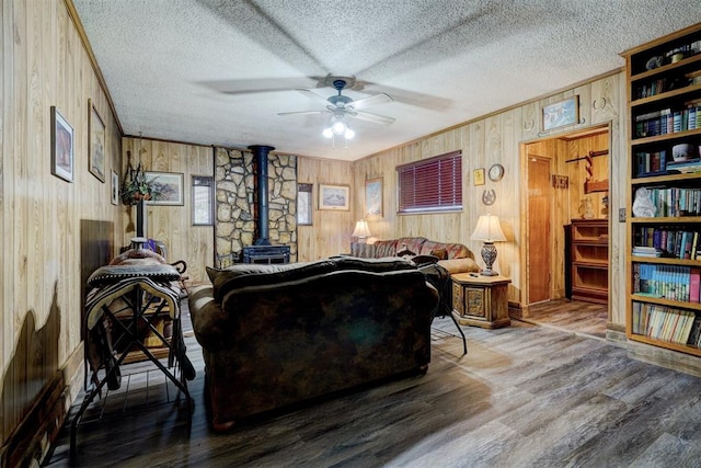 living room featuring a wood stove, wood walls, a textured ceiling, and hardwood / wood-style flooring