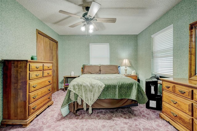 bedroom with a textured ceiling, carpet floors, and ceiling fan