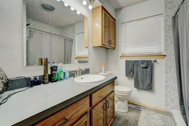 bathroom with hardwood / wood-style floors, vanity, toilet, a textured ceiling, and walk in shower