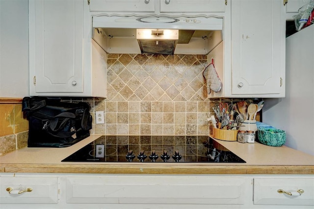 kitchen with backsplash, black electric cooktop, and white cabinetry