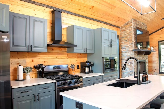 kitchen with appliances with stainless steel finishes, wooden walls, a center island with sink, wooden ceiling, and wall chimney exhaust hood