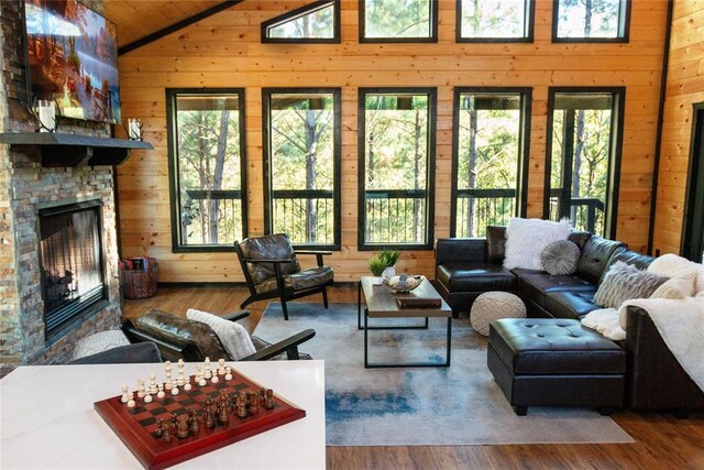 living room featuring wood walls, wood ceiling, high vaulted ceiling, a fireplace, and hardwood / wood-style floors