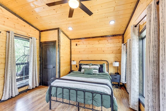 bedroom with ceiling fan, lofted ceiling, wood-type flooring, and wooden walls