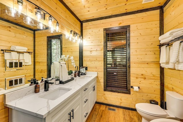 bathroom with hardwood / wood-style flooring, wooden walls, vanity, wooden ceiling, and toilet