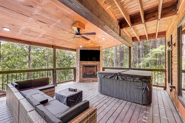 wooden terrace with an outdoor living space with a fireplace, a hot tub, and a ceiling fan