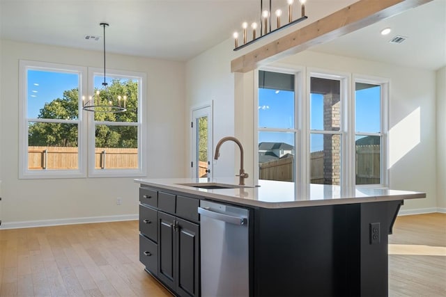 kitchen with sink, light hardwood / wood-style flooring, stainless steel dishwasher, an island with sink, and a chandelier