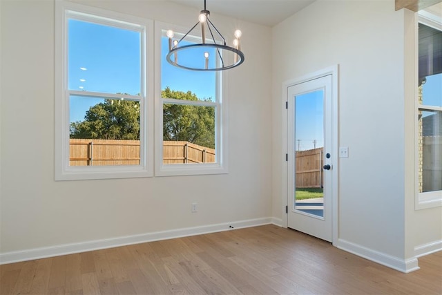 1103 Mount Irving Way, Norman, OK 73071 - unfurnished dining area with light wood-type flooring, healthy amount of natural light, a chandelier, and baseboards