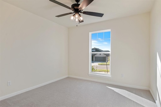 empty room with a wealth of natural light, ceiling fan, and light colored carpet