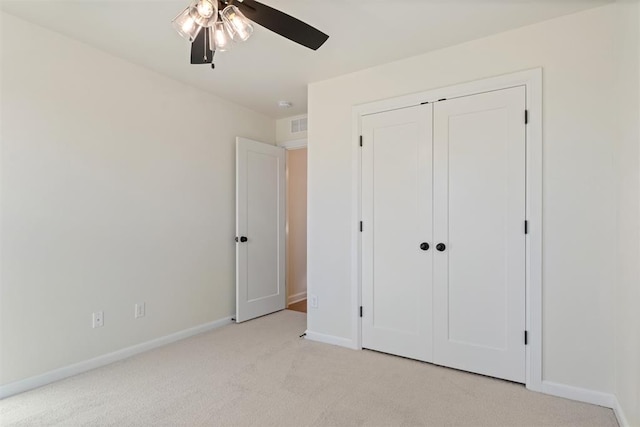 unfurnished bedroom with a closet, light colored carpet, and ceiling fan