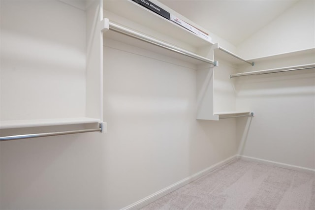 walk in closet featuring light colored carpet and vaulted ceiling